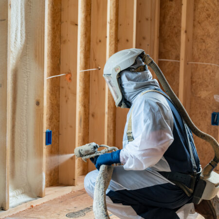 Person spraying white foam on wall